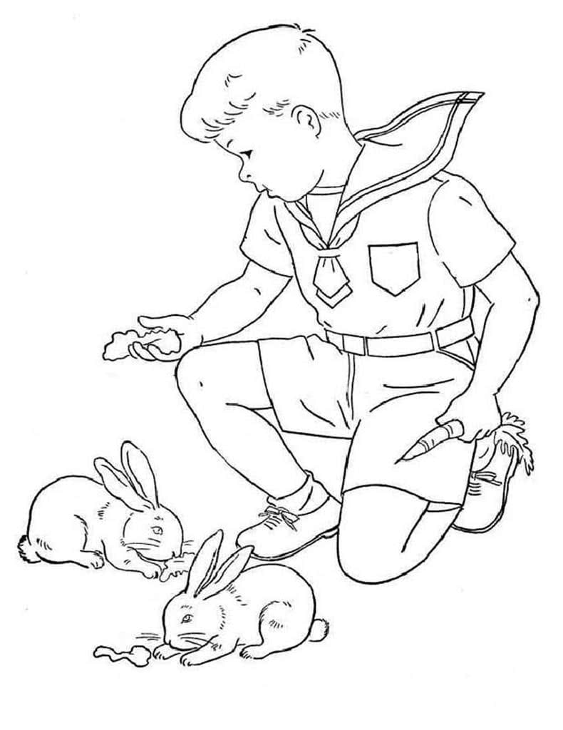 Мальчик кормит двух кроликов
